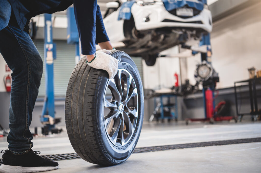 Worker in autobody shop putting tire on a car using a lift that was financed