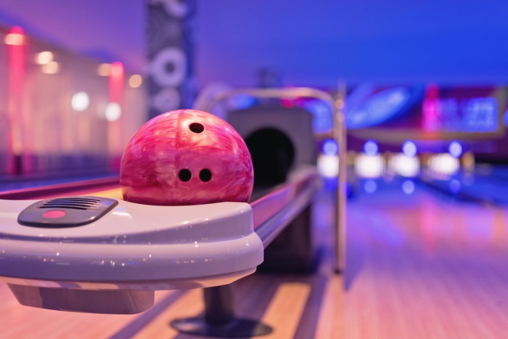 A bowling ball resting in a ball return machine.